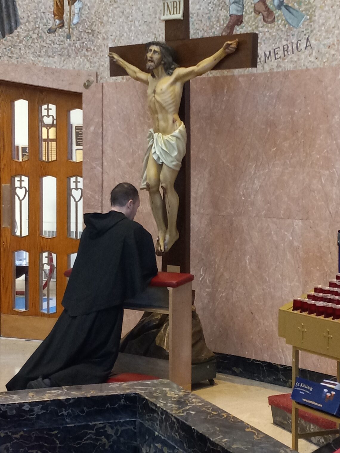 A friar on pilgrimage kneeling before the crucifix